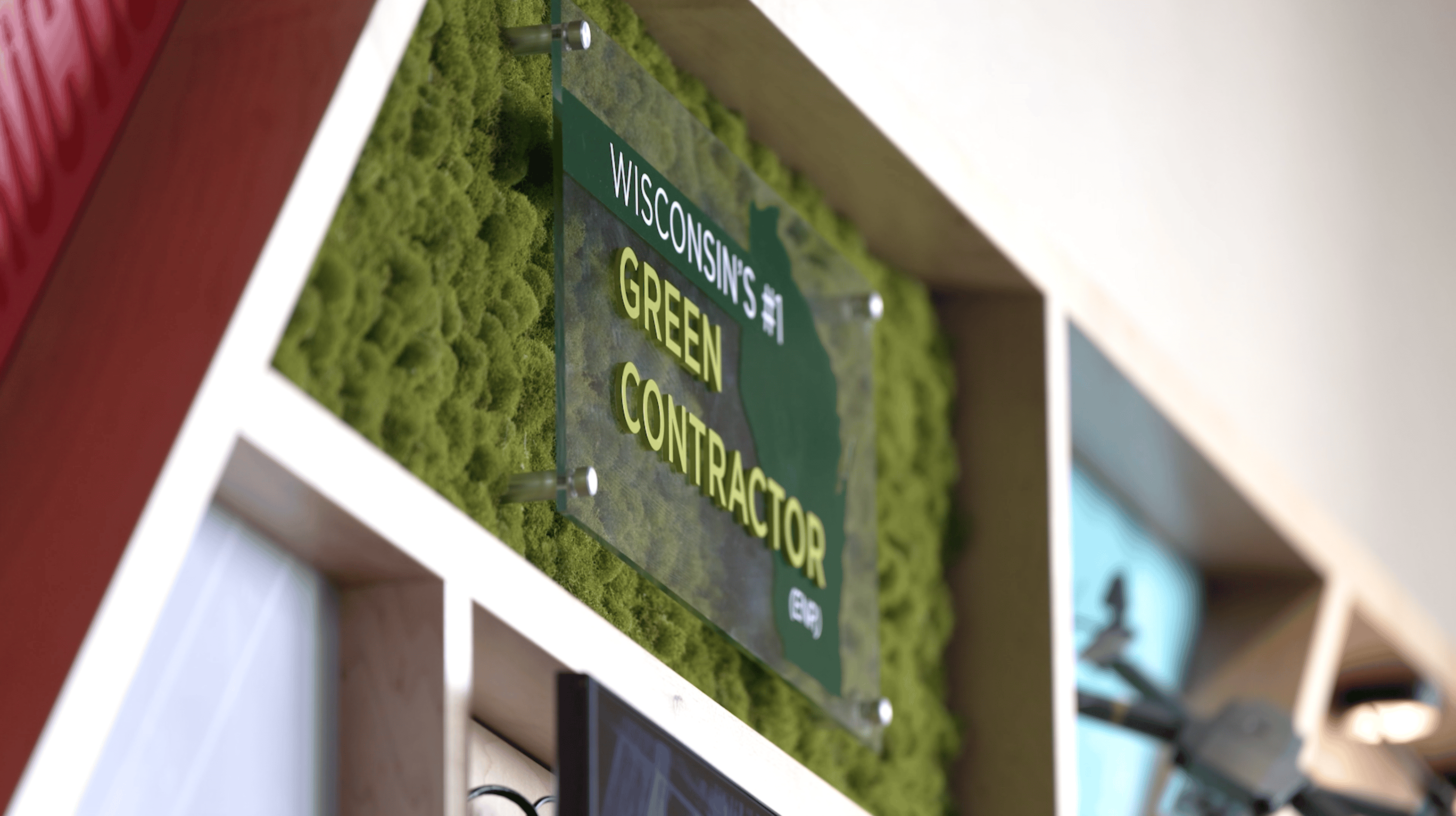 Wall display at Findorff headquarters showcasing Thysse’s facility branding work. Features green moss backdrop with a transparent sign reading 'Wisconsin’s #1 Green Contractor (ENR)' overlaid on a silhouette of Wisconsin.